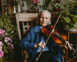 Betty Shalla, Barrys Bay, age 100. Sitting in her living room, Betty, a long-time lover of dancing and music, pulls out her fiddle to play us a tune.