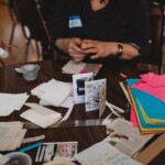 A woman builds a zine from materials on a table.