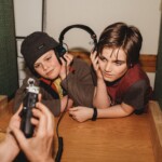 Two boys listen to a recording on one set of headphones.