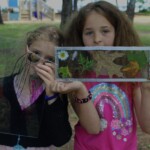 Two girls hold up a glass art piece