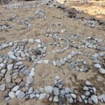 Stones laid out in a pattern on sand.