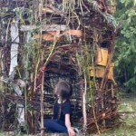 A girl sits in a tower built of plants