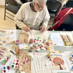 A man paints at a table.