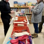 Two people stand beside a table of art supplies.