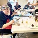 A group of people paint at a table.