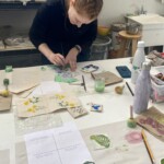 A woman paints small details at a table.