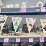 Pennants hang in front of pottery.